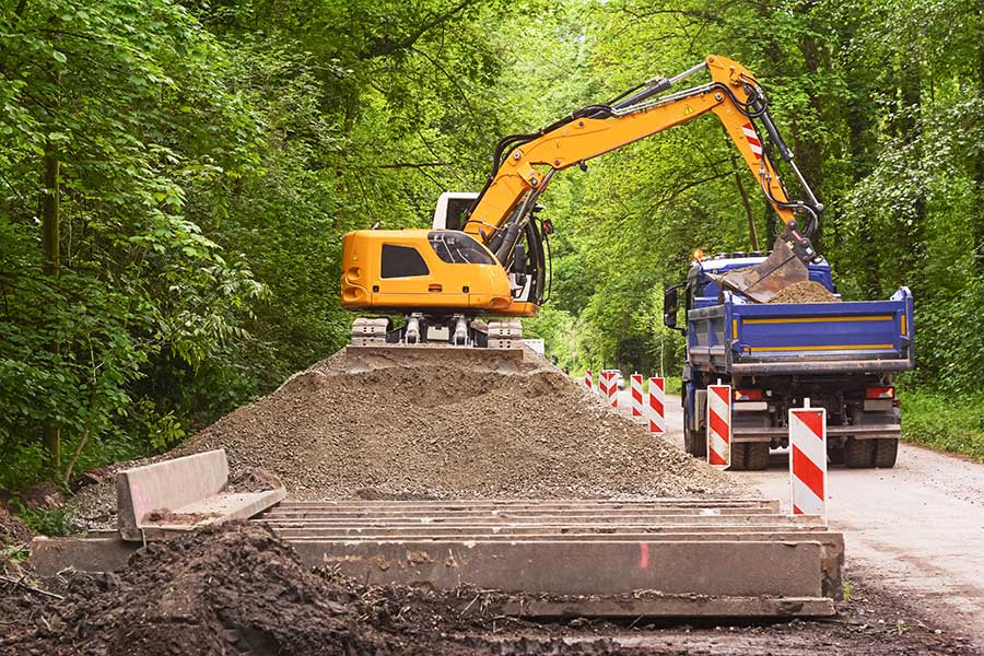 bagger Ein Bagger schaufelt Erde auf einen Lastwagen.